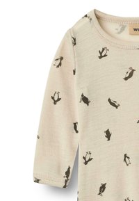 Beżowy bodysuit z długim rękawem o miękkiej teksturze, z powtarzającym się czarnym wzorem pingwinów. Okrągły dekolt z przeszytymi brzegami.