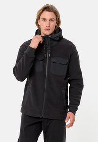 Jacket in pile nero con chiusura a zip, due tasche sul petto e tasche laterali. Presenta un cappuccio e un tessuto testurizzato con lembi di protezione lisci.