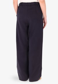 Pantaloni a gamba larga blu navy con vita elastica, tasche laterali e una texture di tessuto liscia, mostrati da dietro.