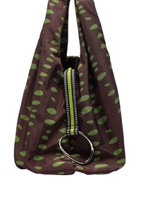 Miękka brązowa torba z materiału, pokryta rozrzuconymi zielonymi owalnymi wzorami, z czarno-zieloną paskiem wciągniętym do srebrnego pierścienia D.
