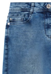 Gros plan sur le devant d'un jean en denim bleu avec un bouton visible, des passants de ceinture, deux poches avant et des détails de couture.