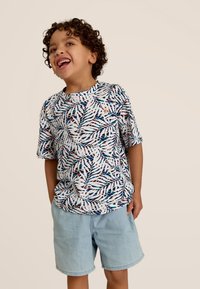 Korte mouwen shirt met een witte basis met een kleurrijk bladerenpatroon. Gecombineerd met lichtblauwe denim shorts. Zachte stof, casual pasvorm.