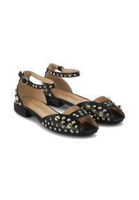 Zapatos negros planos con los dedos cortados, adornados con espigas doradas en forma de pirámide. Cuentan con correas en el tobillo y una plantilla acolchada color beige.