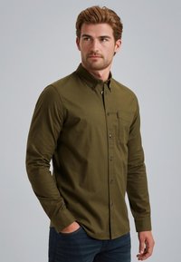 Camicia verde oliva a maniche lunghe con chiusura a bottoni, taschino sul petto e colletto. Realizzata in un tessuto morbido con una texture liscia.