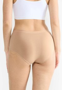 Beige Baumwollslips mit glatter Textur, mittelhoher Taille und vollflächigem Design. Keine sichtbaren Nähte oder Muster.