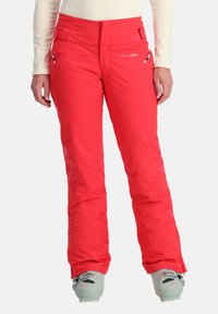 Rote Skihosen haben ein elegantes Design mit Reißverschlusstaschen, strukturiertem Stoff und einer engen Passform. Der Saum hat eine leichte Weite, ideal für Skischuhe.
