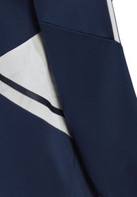 Tessuto blu navy con un design testurizzato, che presenta un pannello diagonale bianco e dettagli neri. Il materiale appare liscio ed elastico.