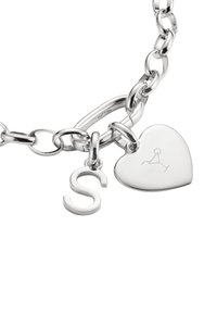 Bracelet en chaîne argentée avec un pendentif en forme de cœur et un charme en forme de lettre 'S', le tout avec une finition brillante et des surfaces lisses.