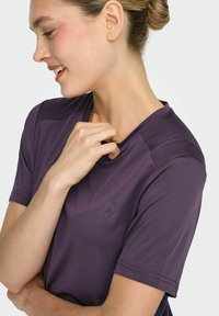 Paarse sport-T-shirt met een gladde textuur, korte mouwen en mesh-accenten op de schouders. Heeft een ronde hals en logodetail.