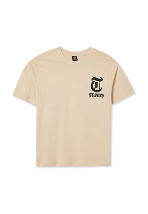 T-shirt beige a maniche corte con scollatura rotonda, con testo in stile gotico nero "T" e "TRUST" sul lato sinistro del petto.