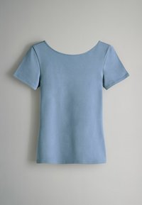 Hellblaues Baumwoll-T-Shirt mit kurzen Ärmeln, einem weiten runden Halsausschnitt und einer glatten Textur, das vor einem neutralen Hintergrund hängt.