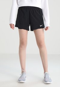 Pantalones cortos deportivos negros con cintura elástica, con un logo blanco de Nike en la parte inferior izquierda. La tela parece suave y ligera.