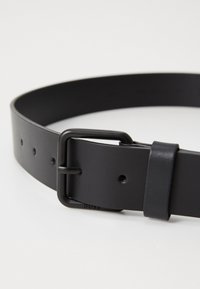 Svart lærbelte med matt finish, rektangulær metallspenne og justeringshull. Enkel design uten ytterligere mønstre eller aksenter.