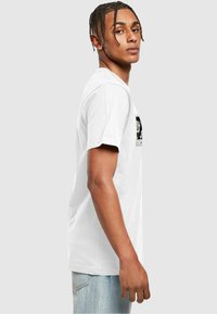 Hvid bomulds T-shirt med korte ærmer og rund halsudskæring, prydet med et sort-hvidt grafisk print på forsiden. Casual pasform.
