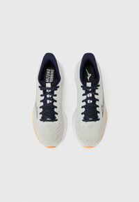 Baskets de course gris clair avec un dessus texturé, des lacets bleu marine et un intérieur noir. Possède des accents orange sur les semelles et un logo sur la languette.