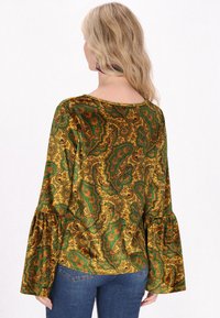 Top a maniche lunghe, verde e oro con motivo paisley, collo rotondo e maniche a campana. Tessuto morbido con una finitura leggermente vissuta.