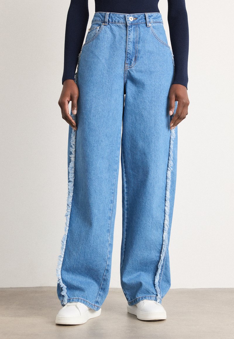 Helleblaue Denim-Hosen im weit geschnittenen Style mit ausgefransten Seitennähten und hoher Taille. Abgeschlossen mit einem Knopfverschluss und klassischem Fünf-Taschen-Design.