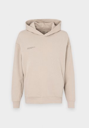Beige hoodie featuring a front kangaroo pocket, long sleeves, and a hood with a subtle text detail on the chest. Soft, smooth fabric texture.