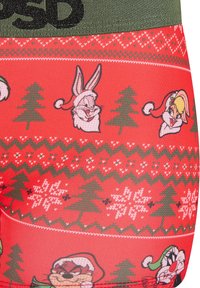 Tessuto rosso con alberi di Natale verdi e fiocchi di neve bianchi, che presenta coniglietti e personaggi con cappelli di Babbo Natale in un motivo festivo.