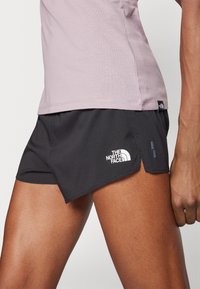 Juodos sportinės šortai su tekstūruotu dizainu, su baltu "The North Face" logotipu ir padalintu iškirpimu, kad būtų lengviau judėti.