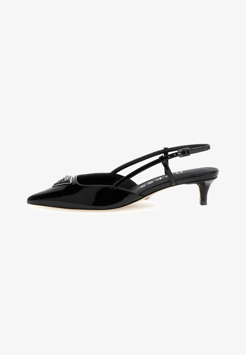 Escarpin slingback en cuir verni noir à bout pointu, petit talon kitten et emblème décoratif sur l'orteil.