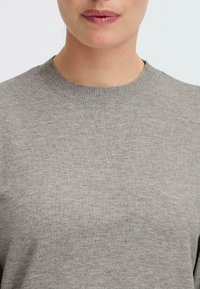 Gray crew-neck sweater featuring a smooth texture and ribbed collar, close-fitting design, with no visible patterns or embellishments.