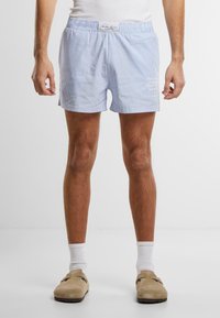Shorts de bain rayés bleu clair avec une taille élastique, ornés d'un logo blanc et d'un fit décontracté, fabriqués en tissu doux.