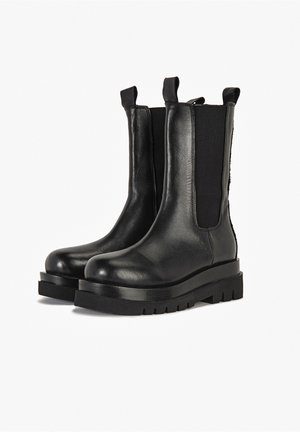 Zwarte leren enkellaarsjes met elastische zijpanelen, aantreklussen en dikke rubberen zolen. Gladde textuur met een afgerond ontwerp van de neus.