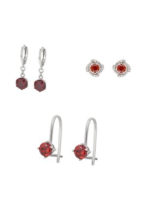 Trzy pary srebrnych kolczyków z czerwonymi kamieniami szlachetnymi: wiszące okrągłe kamienie, okrągłe sztyfty z małymi przezroczystymi kamieniami oraz proste haczyki z okrągłymi kamieniami.