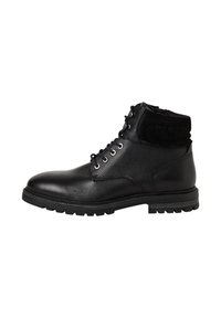Bottine en cuir noir avec col rembourré, lacets à l'avant, œillets en métal et semelle en caoutchouc robuste, présentée en profil latéral sur fond blanc.