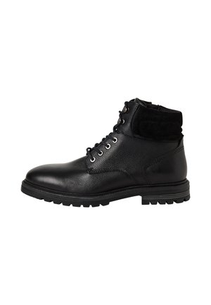 Botín de cuero negro hasta el tobillo con cuello acolchado, frente con cordones, ojales de metal y suela de goma resistente, mostrado en perfil lateral sobre fondo blanco.