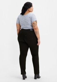 Svarta skinny jeans med midja som sitter något högre, med subtila stygn. Matchas med en figurnära, kortärmad topp med blått mönster.