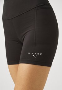Shorts sportivi neri realizzati in tessuto elasticizzato. Caratterizzati da una vita alta, cuciture piatte e loghi bianchi di HYROX e Puma sui lati.