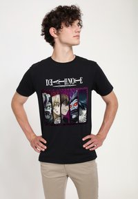Camiseta de algodón negra con un diseño gráfico colorido de "Death Note" con personajes sobre un fondo púrpura y negro. Mangas cortas.
