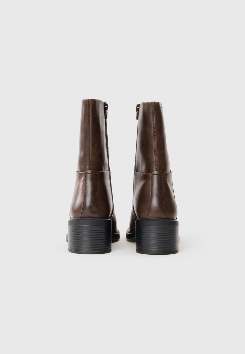 Brązowe skórzane buty za kostkę z okrągłym noskiem, bocznym zamkiem błyskawicznym i przeszywanym czarnym obcasem blokowym, o gładkiej, wypolerowanej fakturze.