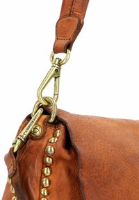 Borsa a mano in pelle marrone con superficie texturizzata, dotata di hardware in ottone e dettagli con borchie lungo il bordo. Fibbia regolabile attaccata.