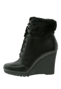 Bottines compensées en cuir noir avec un revers en fausse fourrure, un bout rond, un laçage à l'avant et une semelle compensée texturée.