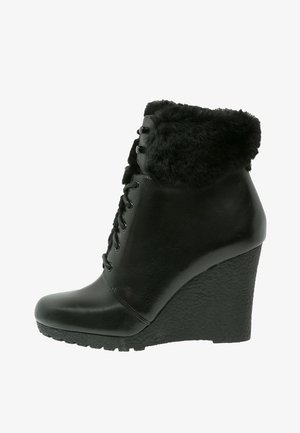 Bottines compensées en cuir noir avec un revers en fausse fourrure, un bout rond, un laçage à l'avant et une semelle compensée texturée.