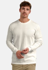 Weißer strukturierter Strickpullover mit horizontalen, gerippten Akzenten. Verfügt über lange Ärmel und einen Rundhalsausschnitt. Dezenter Kontrast in den Strickmustern.