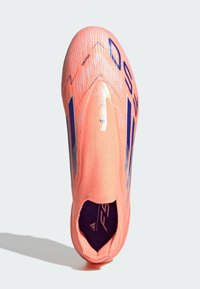 Zapatilla deportiva de color rosa brillante, tipo slip-on, con Rayas y letras en azul oscuro, parte superior texturizada y cuello similar a un calcetín, vista desde arriba.
