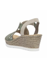 Sandale compensée avec un dessus en daim vert, des découpes décoratives, des accents beiges et un talon tissé texturé dans des tons naturels.