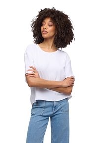 Top bianco a maniche corte con texture, scollatura rotonda, abbinato a jeans in denim blu chiaro. Il top ha una vestibilità morbida e un motivo sottile.