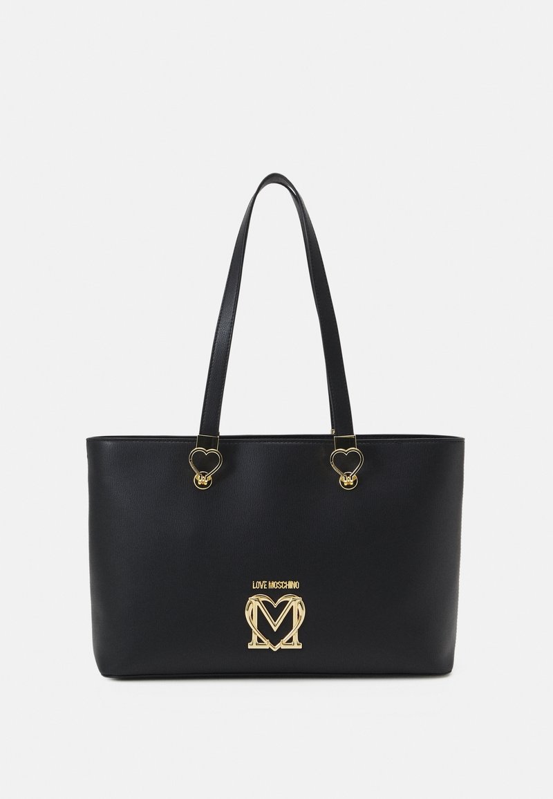 Sac fourre-tout en simili cuir noir avec deux accents en métal doré en forme de cœur et un logo doré central. Forme rectangulaire avec deux poignées.