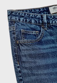 Dark blue denim jeans with a classic five-pocket design, visible stitching, and slight fading. The fabric texture is smooth with a soft finish.