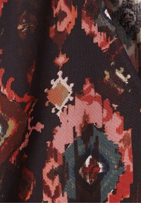 Tissu avec un fond noir présentant un motif abstrait coloré en rouge, rose, turquoise et crème, avec des formes en diamant et florales.