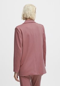 Langärmliger, taillierter Blazer aus weichem, mauvefarbenem Stoff. Mit einem eingeknöpften Kragen und einer glatten Textur sowie einem einzelnen Rückenschlitz.