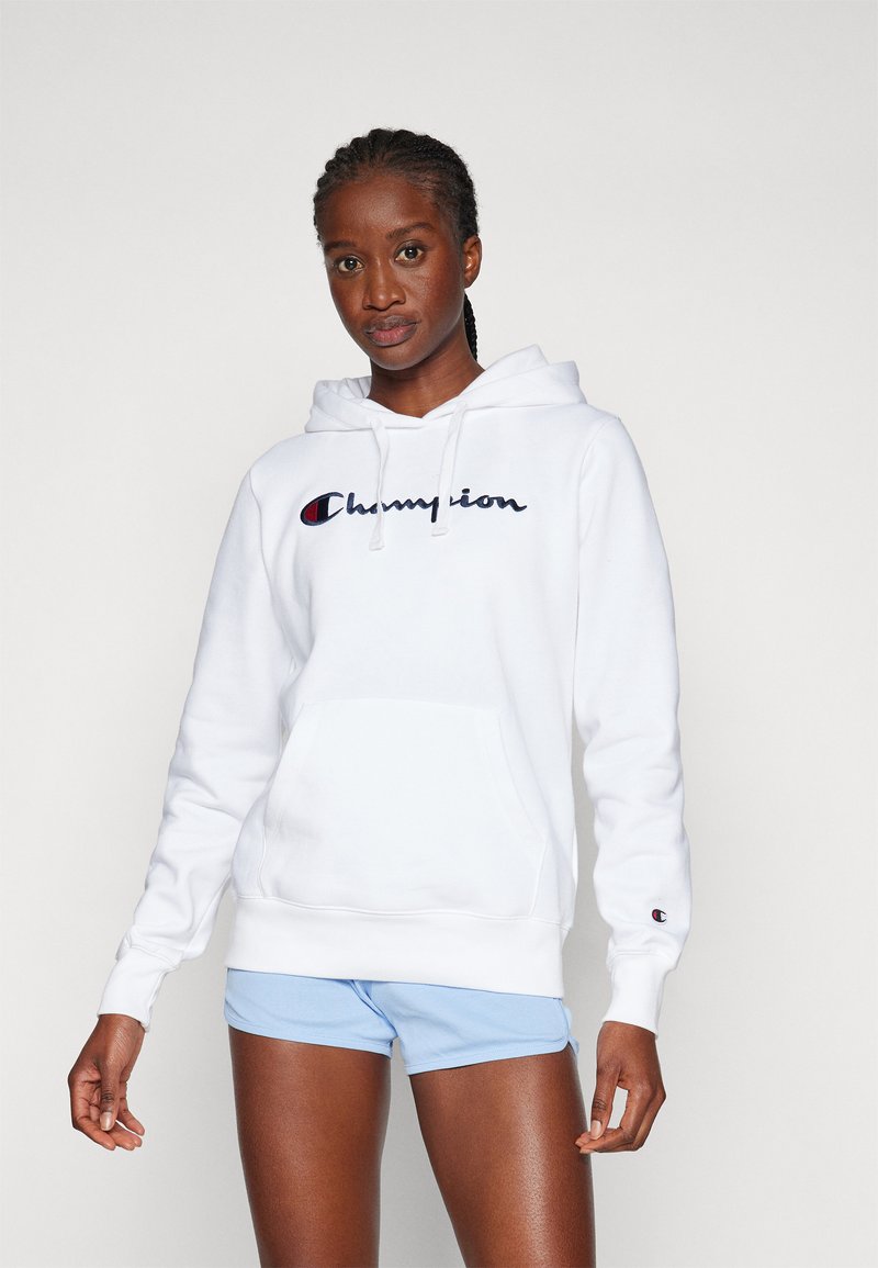 Hvit bomullshoodie med frontlomme, brodert "Champion"-logo i marineblått og rødt, samt ribbestrikkede mansjetter, kombinert med lyseblå shorts.