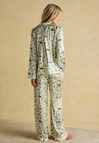 Pajama set in lightweight fabric featuring a pattern of pink cars and green trees. The top has a collar; pants are wide-legged with soft trim.