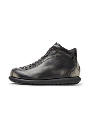 High-top leather shoe in black with a textured finish, featuring laces, rounded toe, and a thick rubber sole with traction.