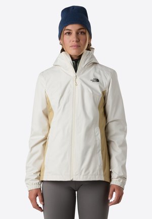 Witte en beige hooded jack met een rits aan de voorkant, elastische manchetten en het The North Face-logo op de linker borst. Draagt over een groene kledingstuk.